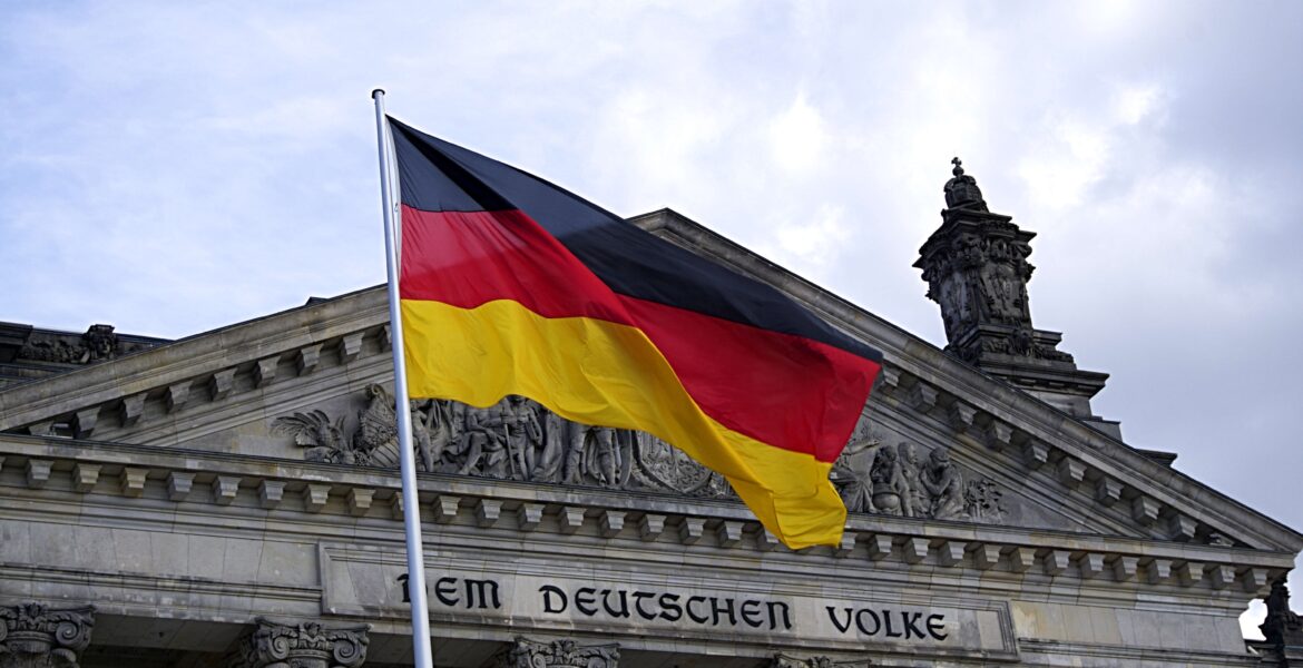 Symbolbild: Deutschland-Flagge mit Reichstagsgebäude im Hintergrund